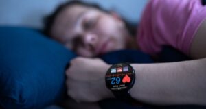 Persona en la cama con un reloj inteligente que mide sus constantes vitales